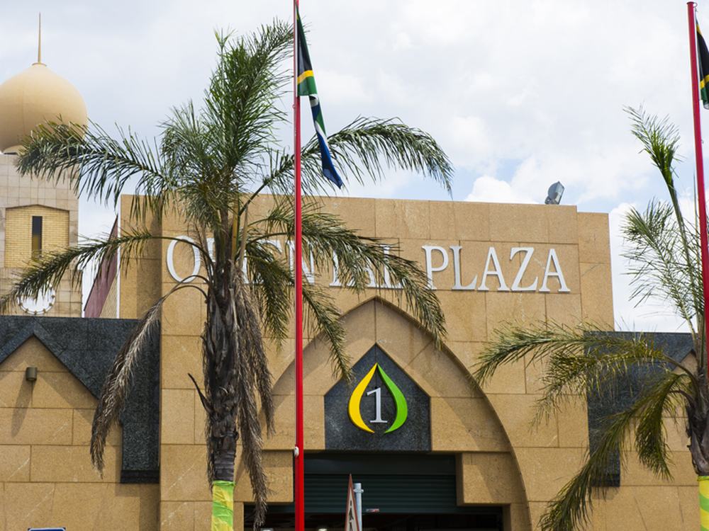 Arched entrance to Oriental Plaza with palm trees and flags